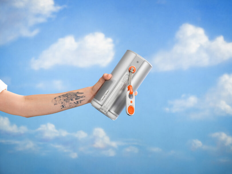 A hand with a tattoo holds a silver Dyson air purifier against a blue sky with scattered clouds, capturing clear detail reminiscent of XGIMI’s high-definition visuals.