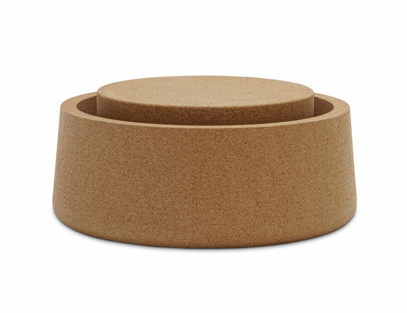 A cylindrical cork container with a matching round lid, both featuring smooth surfaces and a natural brown color.