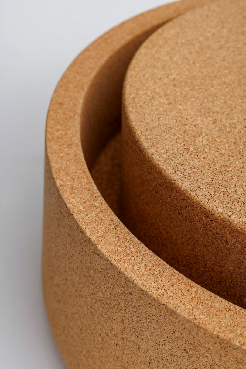 Close-up of two cylindrical cork objects, one nested inside the other, photographed against a neutral background.