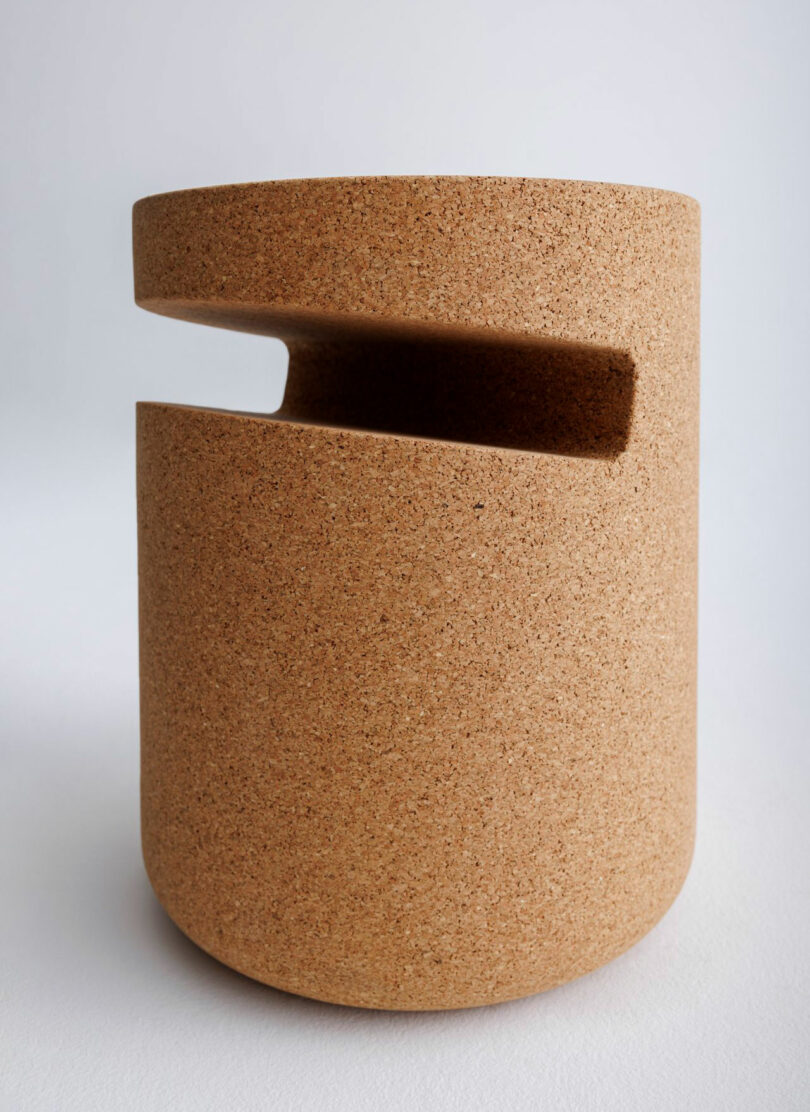 A cylindrical object made of cork with a smooth surface and a horizontal cut-out section near the top.