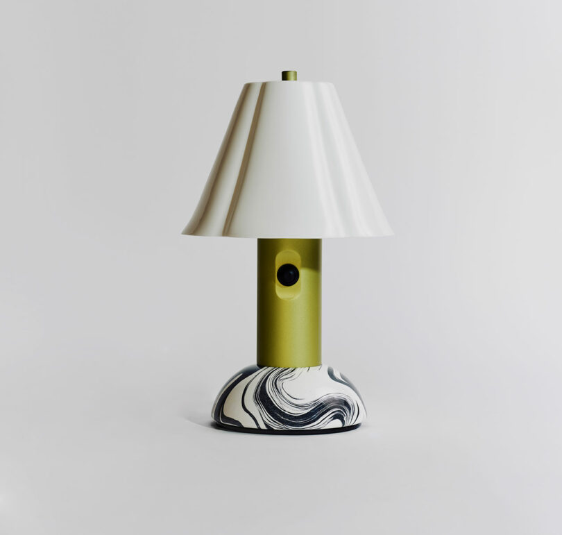 A modern table lamp with a green cylindrical body, white conical shade, and a round marble-patterned base, set against a plain white background.