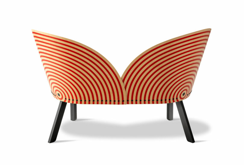 A wooden Bench for Two with a curved backrest featuring red concentric stripes and black legs, photographed against a white background.