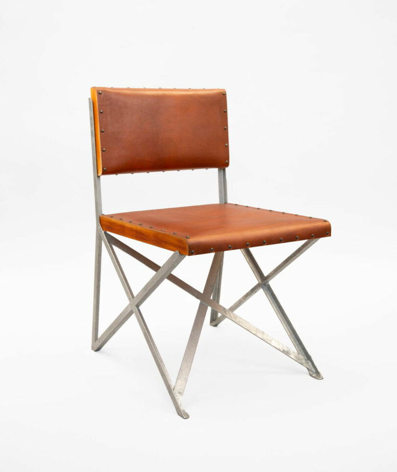 A chair with a metal frame and brown leather seat and backrest, featuring exposed rivets and a minimalist, geometric design.