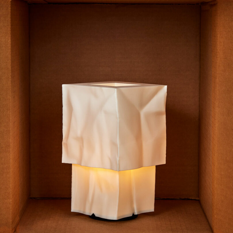 Quadratische, weiße, zerknitterte Farbton von innen beleuchtet, in gewöhnlichen braunen Kartonboxen.