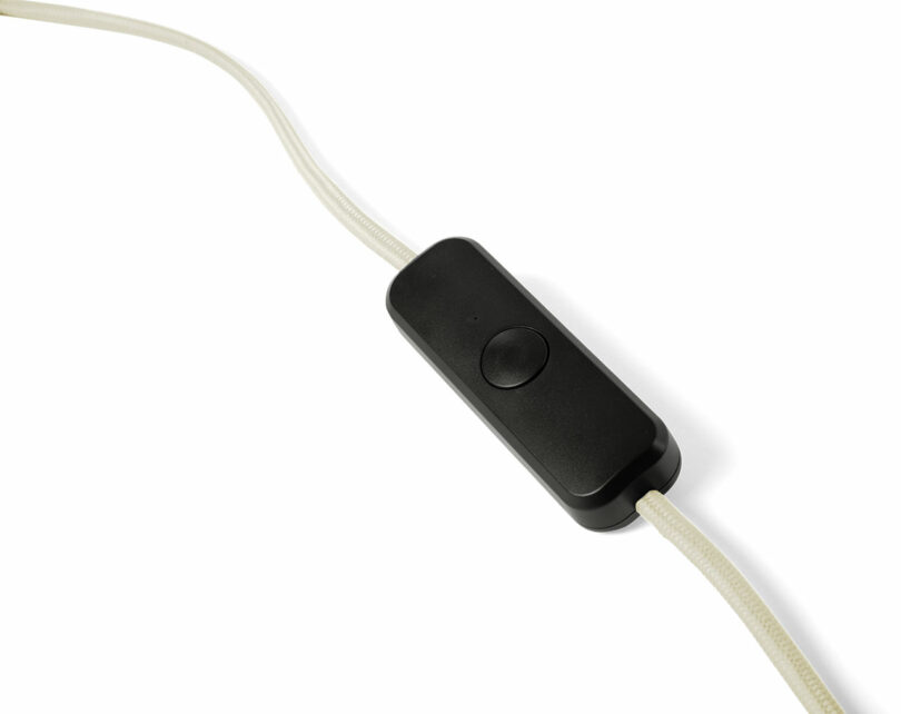 A black inline switch attached to a transparent electrical cord, shown on a white background.