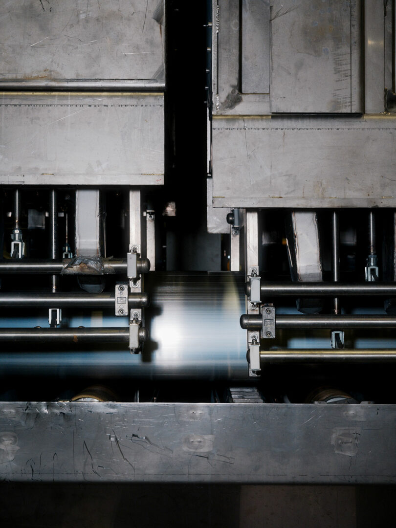 Close-up of an industrial machine in operation, with metal components and a moving part blurred at the center, suggesting high-speed processing.