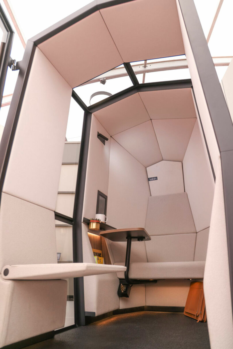 Kabin private office pod with cushioned seats, a small table, glass ceiling, and minimal decor—perfectly designed for focused individual work or meetings.