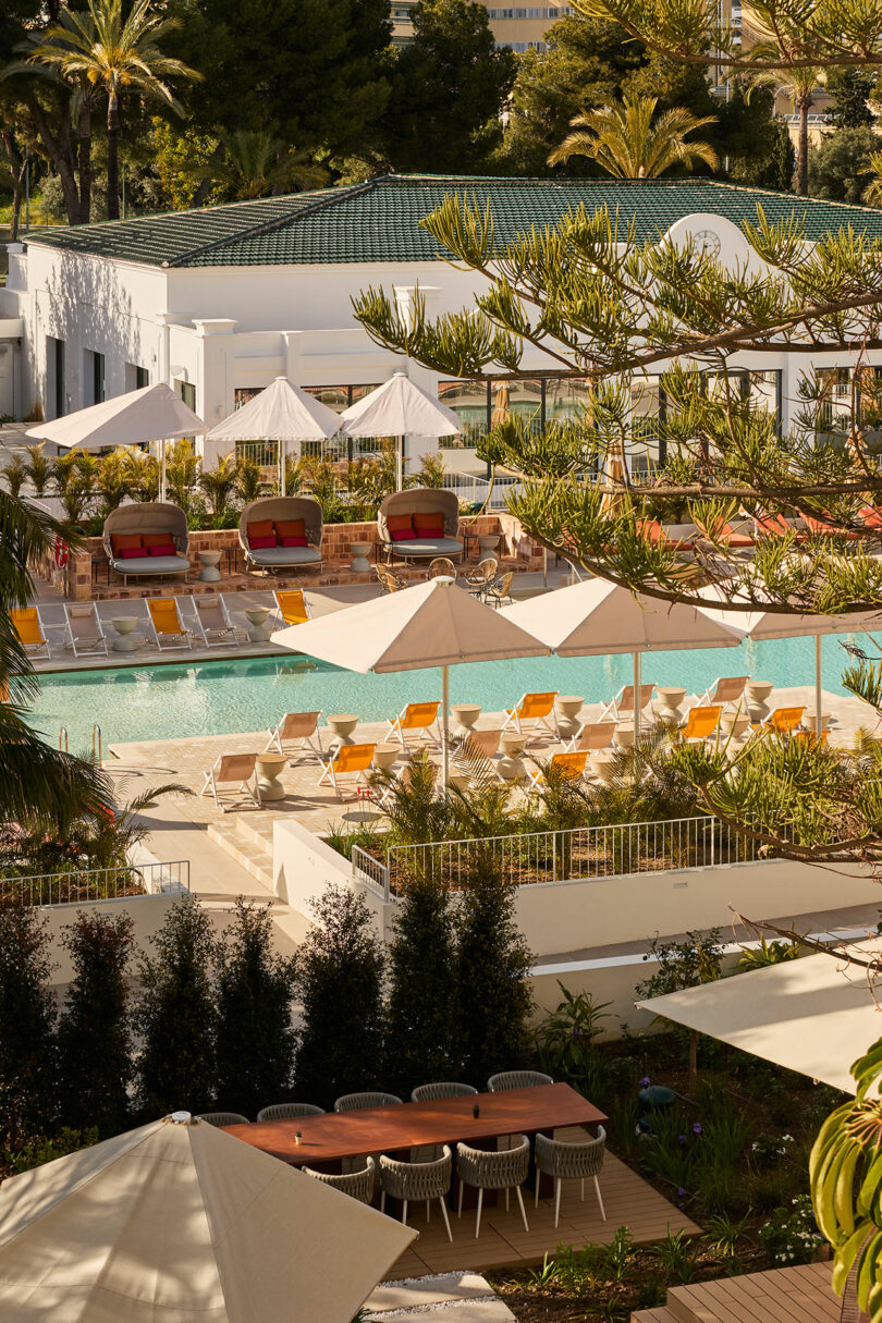 The Kimpton Los Monteros features a stunning hotel pool area with lounge chairs, umbrellas, and cabanas, all surrounded by lush greenery and a striking white building in the background.