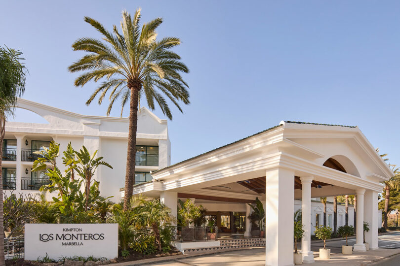 Front view of Kimpton Los Monteros Marbella, featuring elegant white columns, tall palm trees, and a clear blue sky.