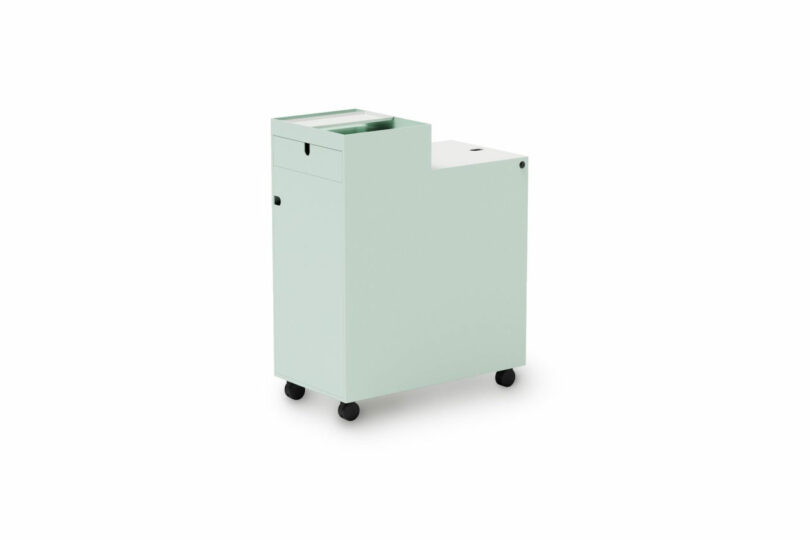 Light green rolling storage cart with a stepped design, featuring drawers and compartments, on four black caster wheels against a white background.