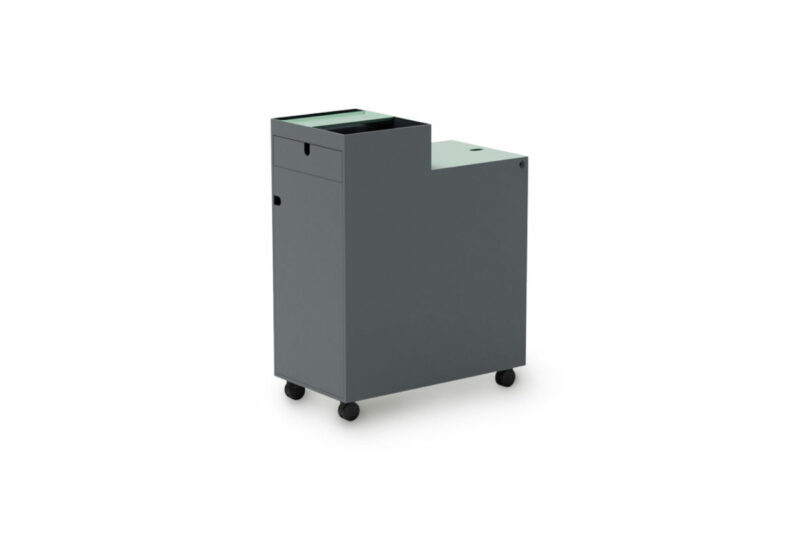 A dark gray, rectangular rolling storage cabinet with a top tray, a drawer, and a closed compartment, set against a white background.