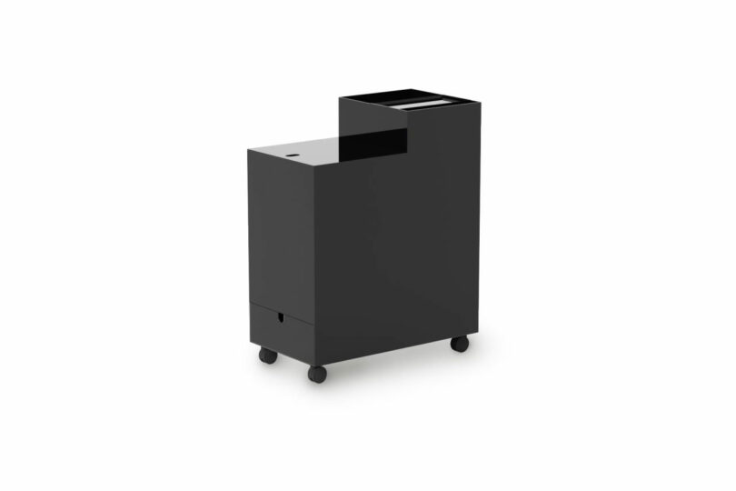 A black, box-shaped rolling cart with a stepped design, featuring a higher open compartment and lower closed section, on four wheels against a white background.
