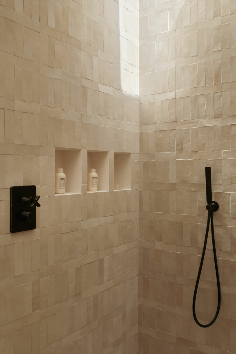 Wrong shower with three built-in shelves by holding the bottles, the black control panel on the wall and a black manual shower coating.