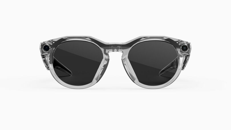 Clear-frame round Meta sunglasses with black lenses, featuring small cameras embedded near the hinges on both sides of the frame.