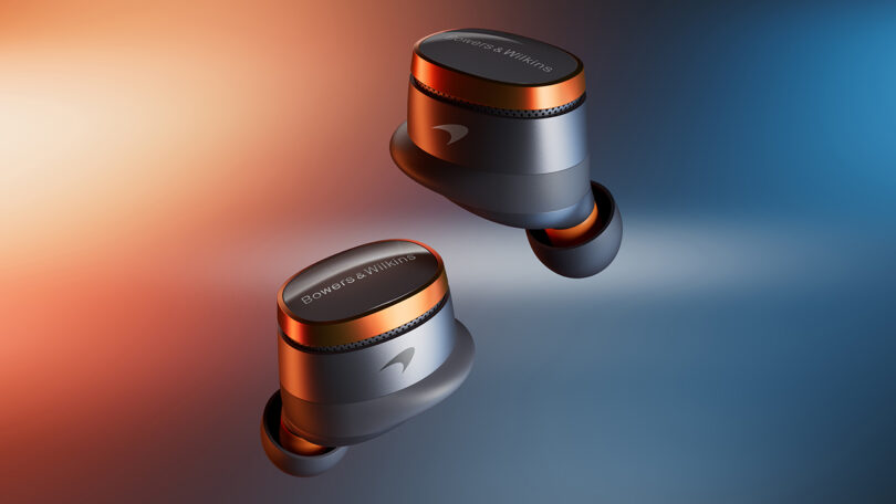 Two metallic wireless earbuds with orange accents, labeled "Bowers & Wilkins," are shown floating against a gradient orange and blue background.
