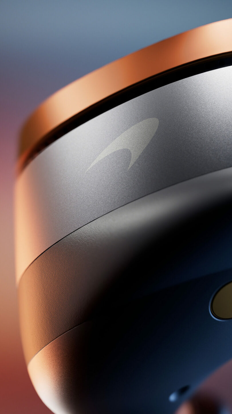 Close-up of a gray and copper device featuring a stylized logo on its surface, shown against a softly blurred background.