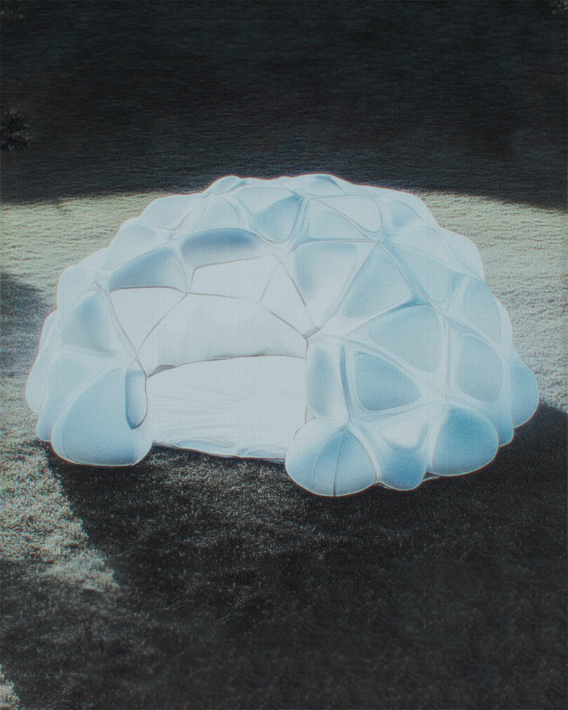 A white, dome-shaped structure with a geometric, inflated pattern sits on grass under daylight.