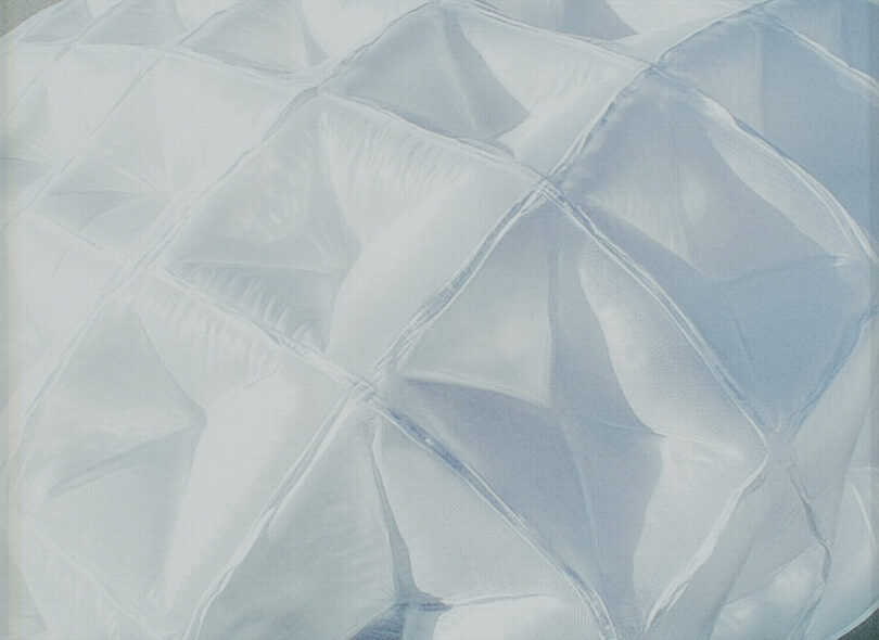 Close-up view of a white, quilted, and padded material with a geometric, puffy texture.