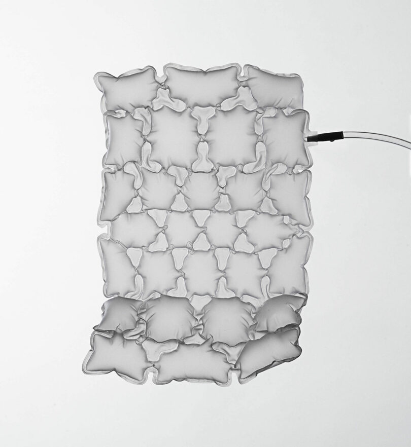A transparent, rectangular inflatable object with interconnected pillow-like sections and an attached tube on a white background.