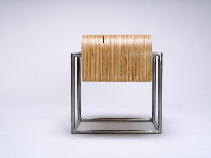 A modern stool with a metal cube frame and a curved wooden seat, photographed against a plain white background.