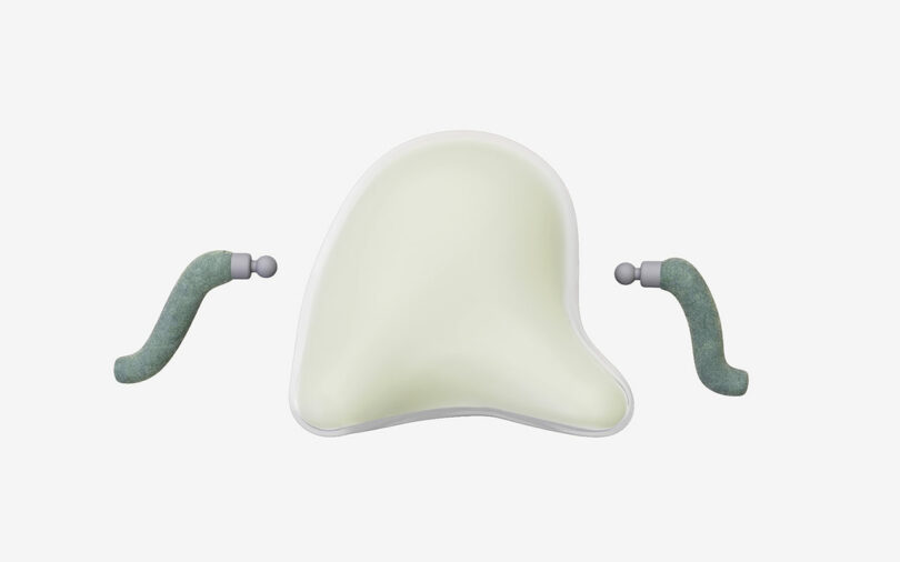 A soft, irregularly shaped white cushion is shown centered, with two curved, greenish-gray handles on either side against a plain background.