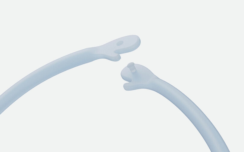 Two curved, translucent plastic pieces with hand-like ends are facing each other against a plain background.