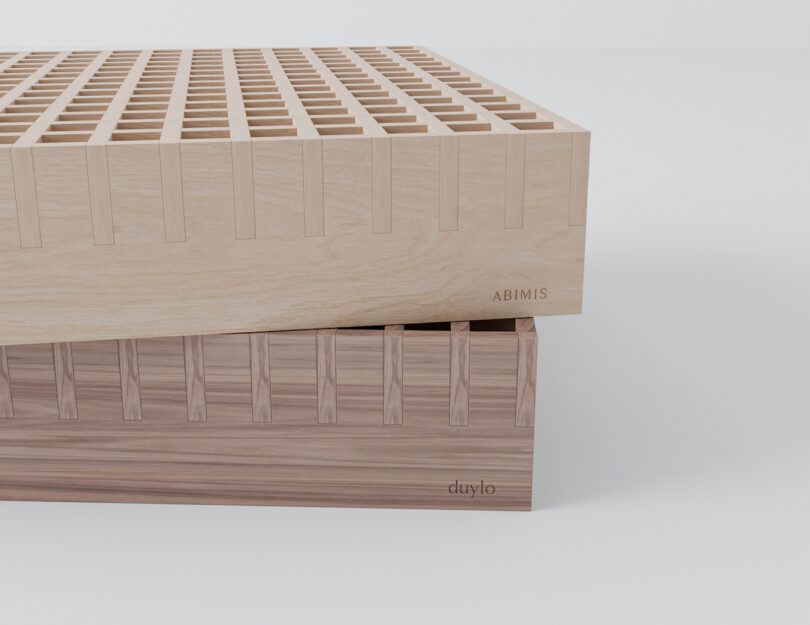 Two wooden blocks with interlocking dovetail joints, one light-colored labeled "ABIMIS" stacked on a darker one labeled "duylo," against a plain white background