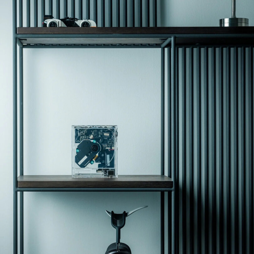 La electrónica ClearFrame con placas de circuito visible se encuentra en rejillas de madera rodeadas de listones negros verticales y otros artículos decorativos mínimos.