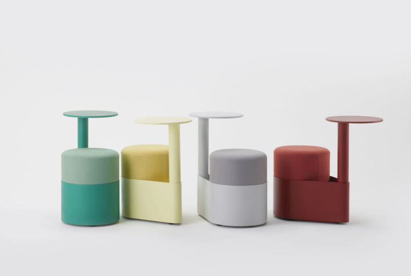 Four modern, cylindrical stools in green, yellow, gray, and red, each with a matching attached side table, are arranged in a row against a plain white background
