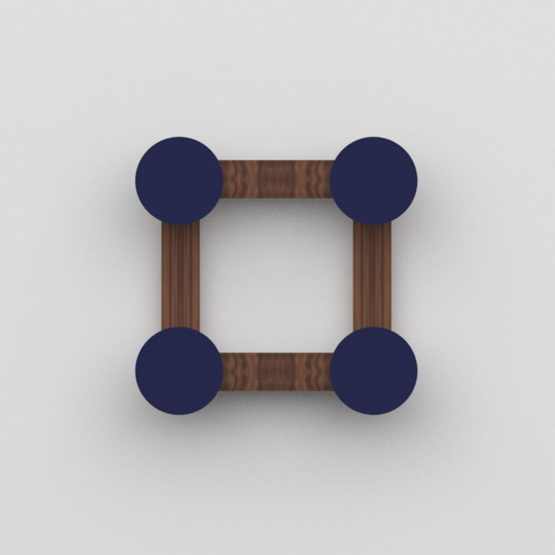 A square wall hook made of four wooden rods connected at the corners by four dark blue circular discs on a plain white background