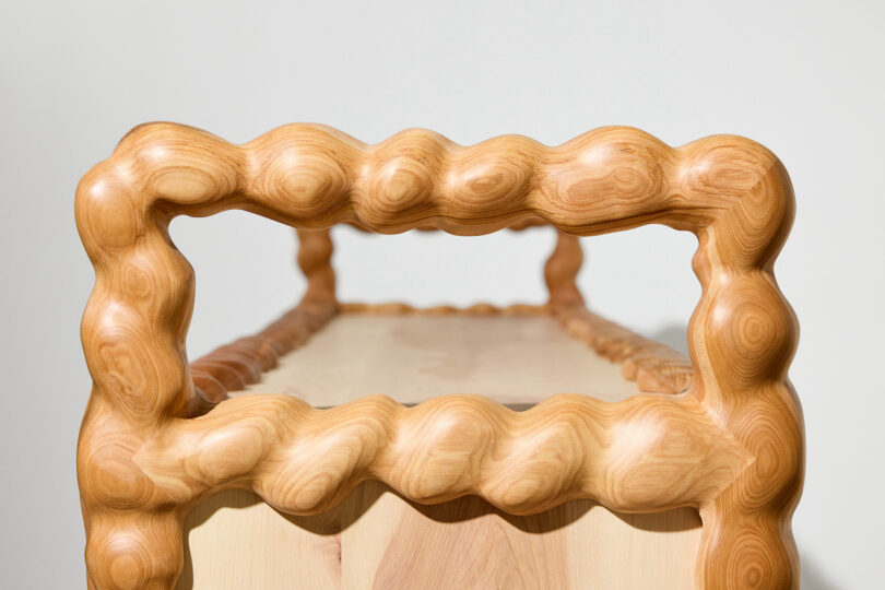 close up of A wooden cabinet featuring wavy, sculpted edges