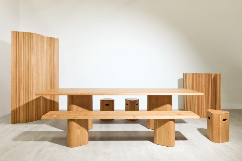 Minimalist wooden furniture set including a table, bench, stools, and room dividers, displayed against a plain white background