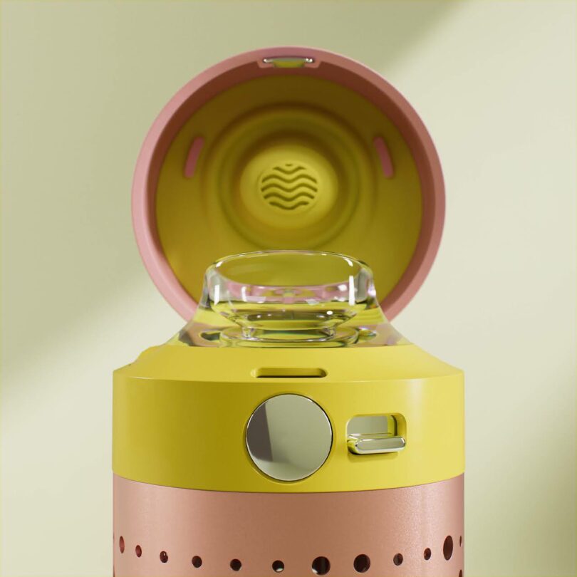 A close-up of a pink and yellow water bottle with its lid open, revealing a clear mouthpiece and round, metallic button on the top