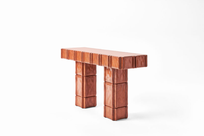 A rectangular, brown console table with block-like, segmented legs and a matching segmented tabletop, set against a plain white background