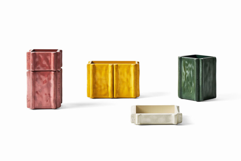 Four rectangular ceramic vases in pink, yellow, green, and white are arranged on a white background