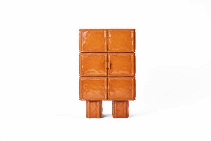Rectangular, glossy orange cabinet with six compartments and two sturdy block legs, set against a plain white background