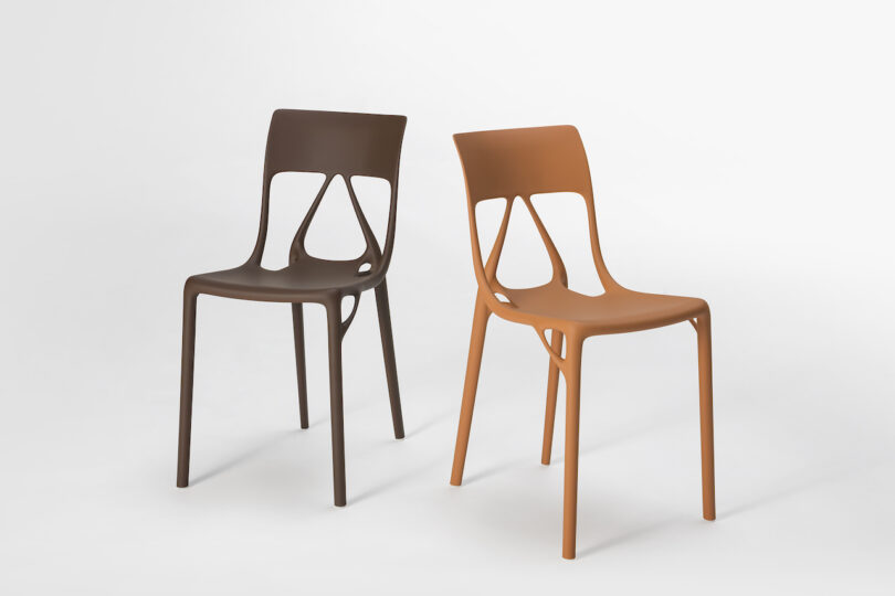 Two modern plastic chairs with cut-out backrests, one in dark brown and one in orange, positioned side by side on a white background