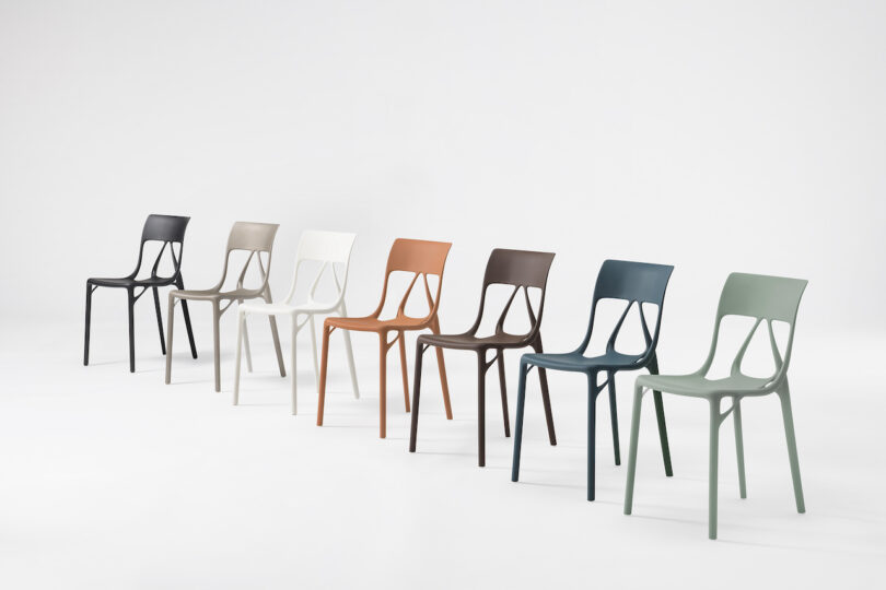 Seven modern plastic chairs in different colors are arranged in a row against a plain white background