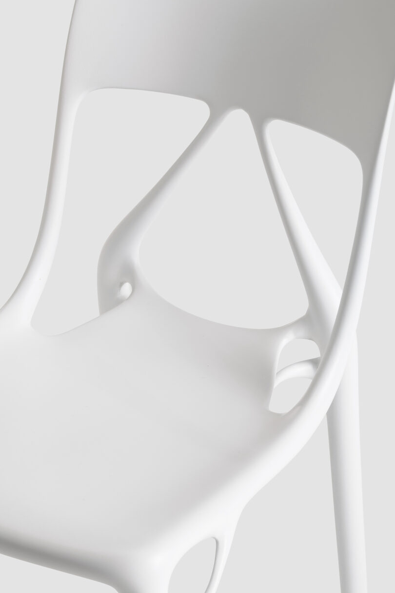 Close-up of a modern white chair with a smooth, curved seat and backrest featuring cut-out geometric shapes