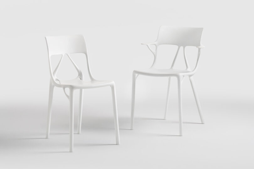 Two modern, white plastic chairs with minimalist design are placed on a plain light background