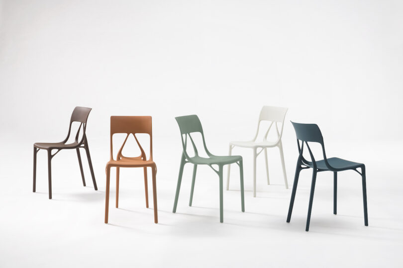 Five modern plastic chairs in different colors are set against a plain white background