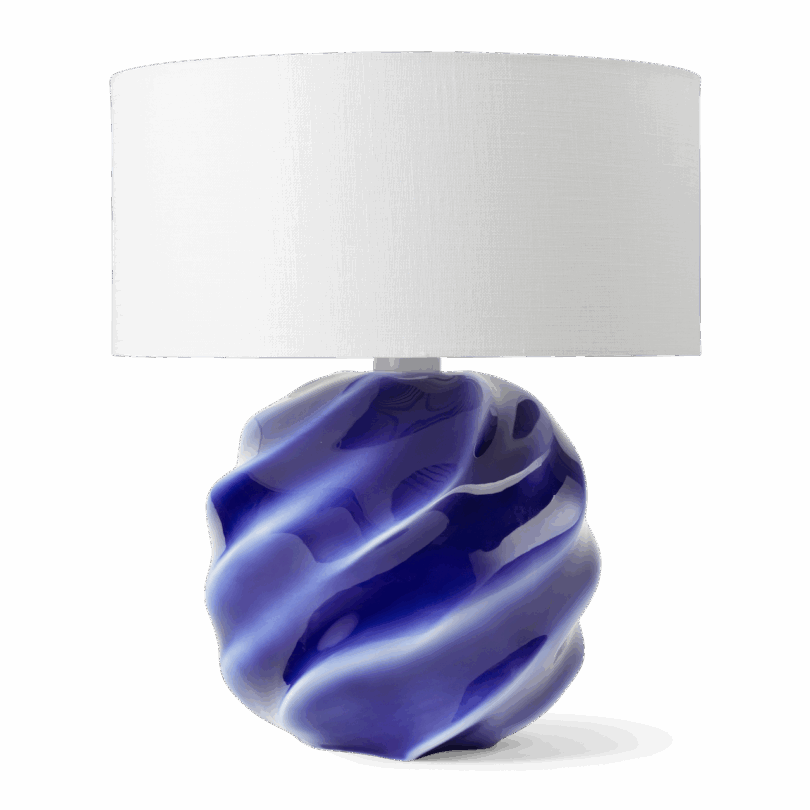 Table lamp with a white cylindrical lampshade and a glossy, wavy, deep blue ceramic base