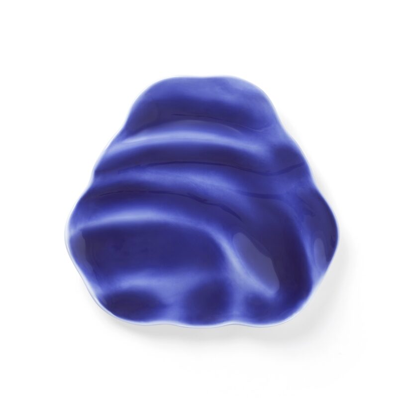 A blue and white ceramic dish with an irregular, wavy shape and a glossy finish.
