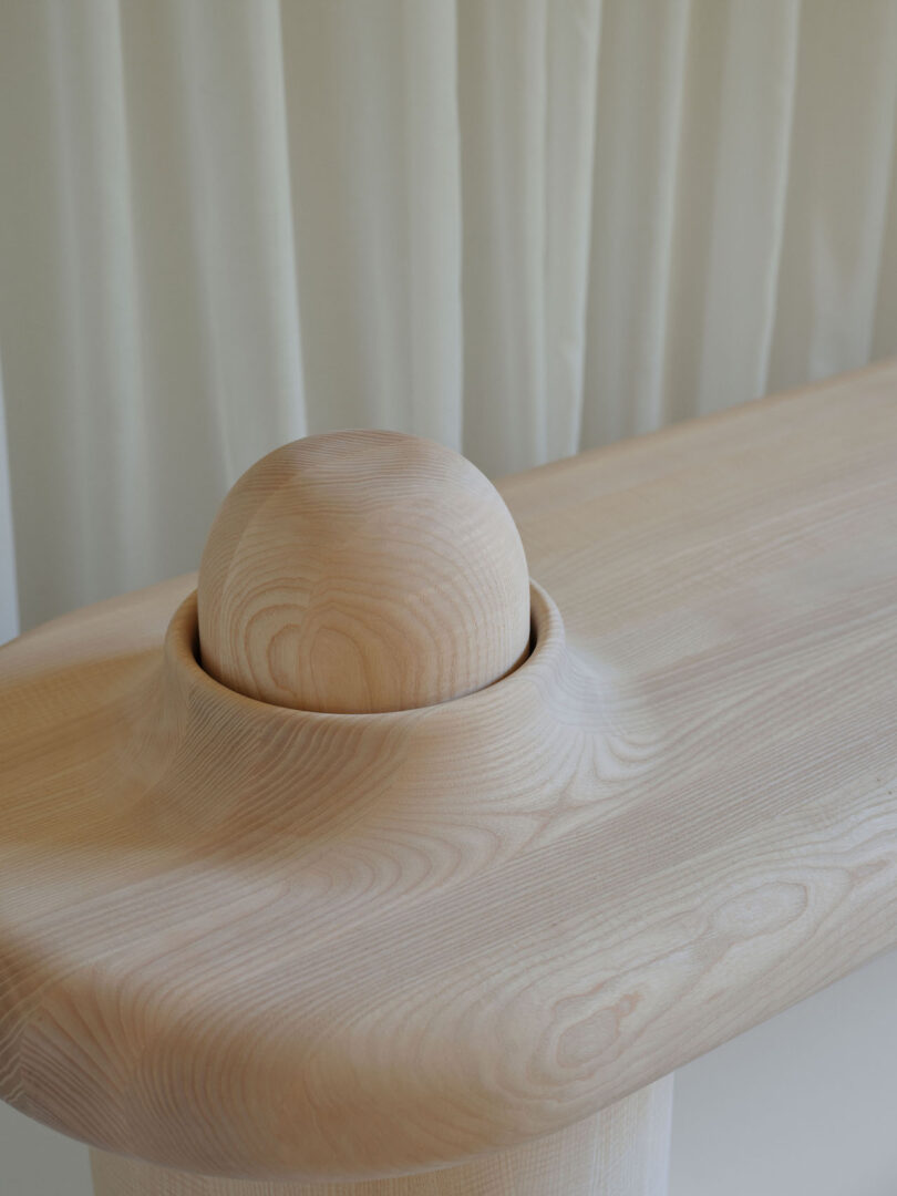 A close-up of a smooth, light wood bench with a rounded edge 