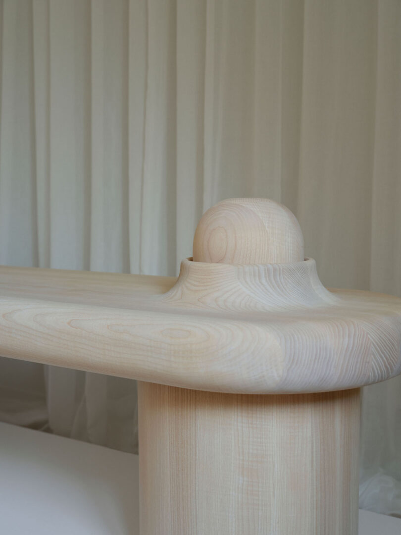 A close-up of a smooth, light wood bench with a rounded edge 