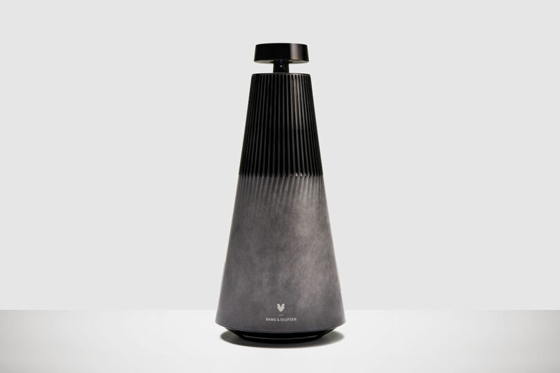 A cone-shaped black and gray Bang & Olufsen speaker with a ribbed upper section and the logo at the bottom, set against a plain light background.