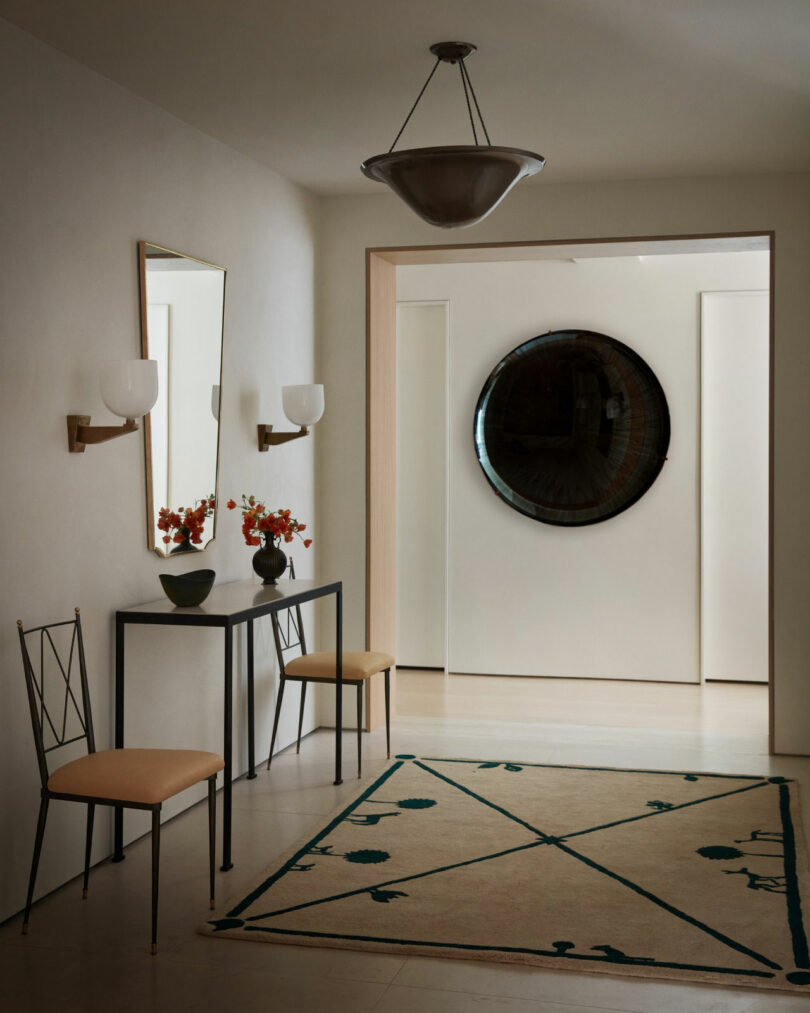 The minimalist hallway Nicki Gitlin has a table consoles, two chairs, geometric mats, wallpaper and a large round mirror on a distant wall.