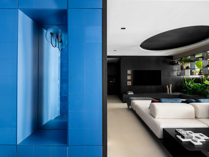 Sala de estar moderna con una característica de pared de azulejos, sofá seccional blanco, pared de acento negro y plantas de interior.