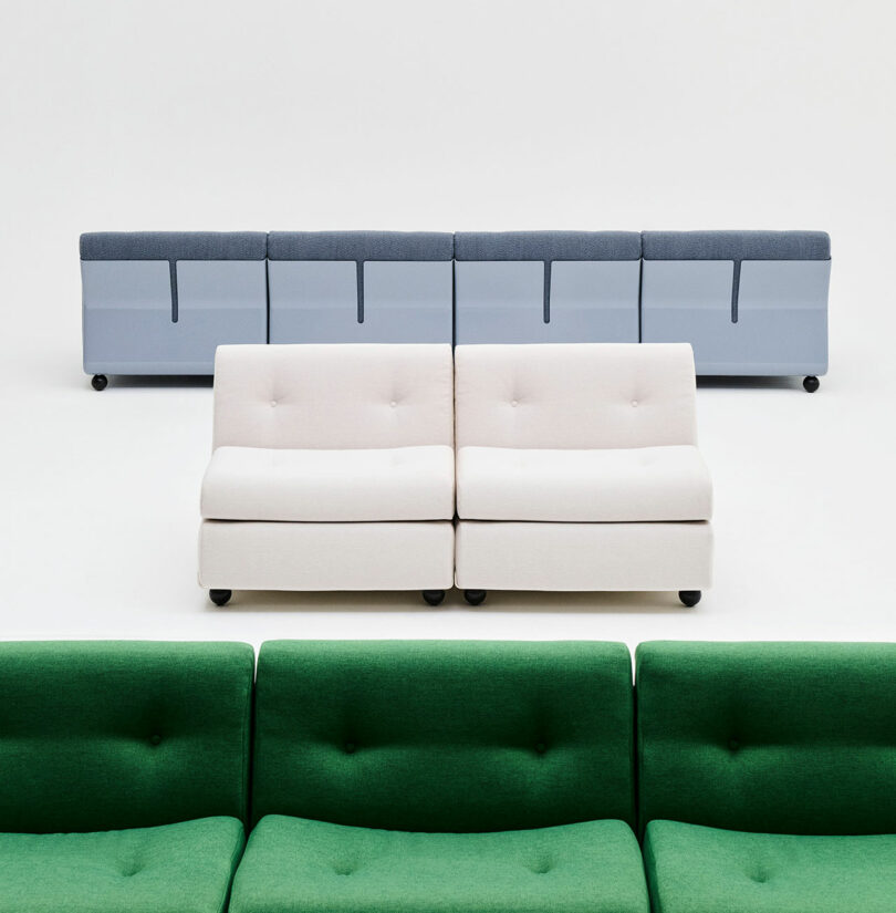 Three rows of modern sofas—green in front, white in the middle, and blue in the back—are arranged on a white background.