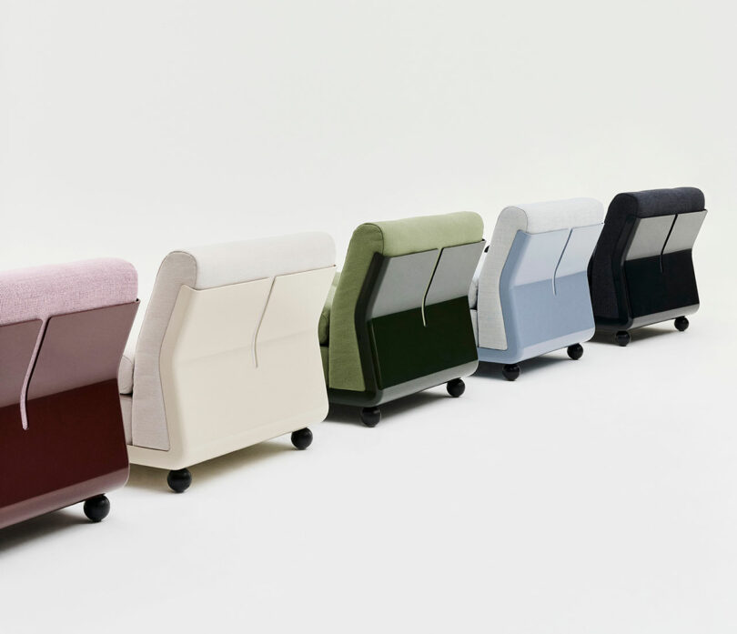 Five upholstered chairs in different colors are arranged in a row, viewed from the back, on a plain white background.
